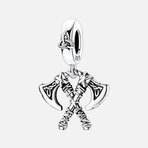 May include: A sterling silver charm featuring two crossed battle axes with intricate knotwork detailing on the blades and handles. The top bail is engraved with a triquetra symbol and the hallmark S925, indicating the silver purity of the piece.