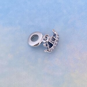 May include: Silver charm in the shape of a gondola with clear crystal accents. The charm has a loop for attaching to a bracelet or necklace.