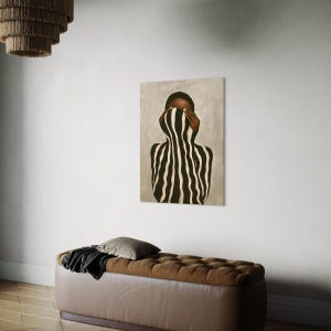 Afrocentric Black woman wall art displayed above a modern sofa in a bright, neutral living room. Minimalist portrait art print with black and white stripes and soft natural light.