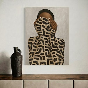 Op de afbeelding: Abstract schilderij van een persoon met een patroon kledingstuk dat hun gezicht bedekt. Het kunstwerk heeft een zwart en bruin ontwerp. Een donkere, getextureerde vaas met een handvat staat op een houten oppervlak.