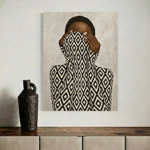 Op de afbeelding: Een artistiek schilderij van een persoon met het gezicht gedeeltelijk bedekt door een zwart-wit patroon kledingstuk. Het kunstwerk wordt tentoongesteld aan een muur boven een houten oppervlak, met een donkere, getextureerde vaas aan de linkerkant.