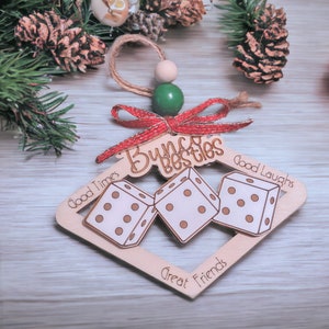 May include: Wooden Christmas ornament shaped like a dice frame with three dice inside. The ornament is decorated with a red bow and the words "Bunch besties", "Good Times", "Good Laughs", "Great Friends".