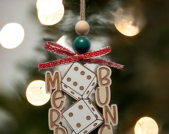 May include: A wooden Christmas ornament with the words "Merry Bunco" and three dice. The ornament is decorated with a red and white ribbon and a green and wooden bead.