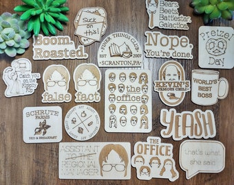 May include: A collection of 15 wooden coasters featuring quotes and images from the popular television show "The Office". The coasters are made of light brown wood and have a variety of designs, including characters from the show, iconic quotes, and logos.