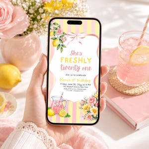 May include: A smartphone displaying a digital birthday invitation with a yellow and white striped background, pink ribbon, lemon and floral illustrations, and the text: She's FRESHLY twenty one, Join us to celebrate, Olivia's 21st Birthday.