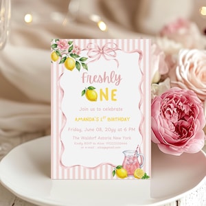 Könnte beinhalten: Rosa und weiß gestreifte Geburtstagseinladungskarte mit dem Text "Freshly ONE" und "AMANDA'S 1ST BIRTHDAY". Sie zeigt Zitronen- und Blumenillustrationen, eine rosa Schleife und eine rosa Limonade.