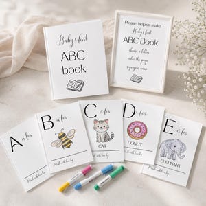 Puede incluir: Un libro blanco titulado Baby's first ABC book, un letrero enmarcado con instrucciones y cinco páginas de actividades individuales etiquetadas de la A a la E con ilustraciones de abeja, gato, dona y elefante, junto a tres marcadores.