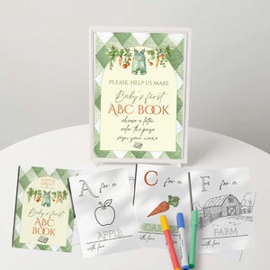 Può includere: Un cartello incorniciato e pagine da colorare per il primo libro ABC di un bambino. Il cartello riporta la scritta "Baby's first ABC BOOK" e le istruzioni per scegliere una lettera, colorare la pagina e firmare il proprio nome. Le pagine da colorare presentano una mela, una carota e una fattoria.