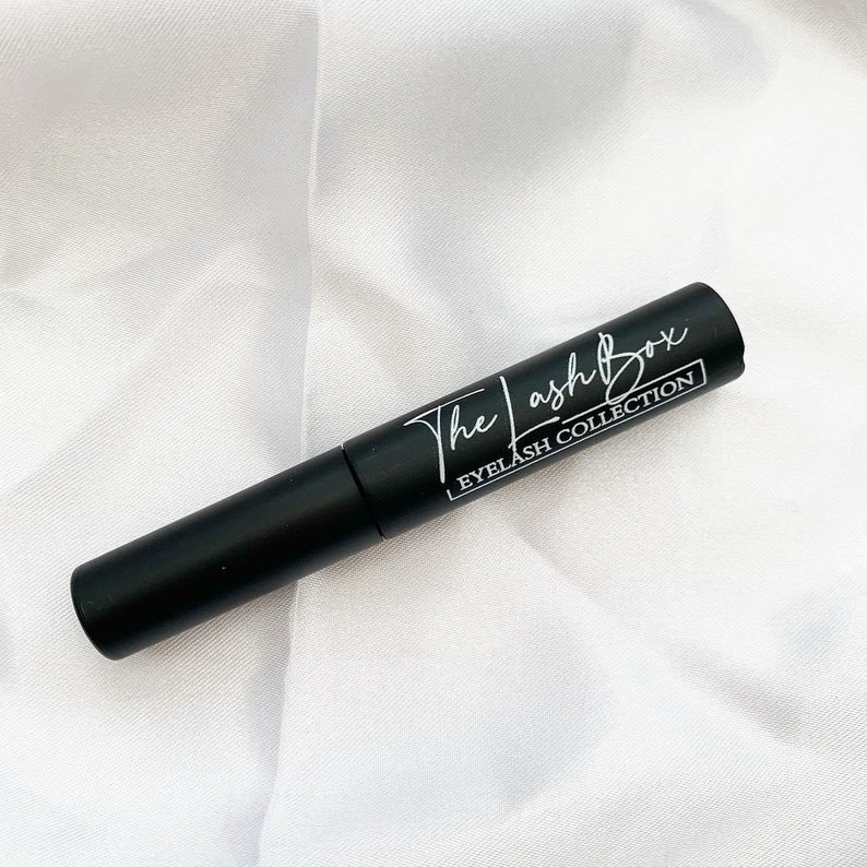 May include: A black tube of lash adhesive with white text that reads "The Lash Box Eyelash Collection".