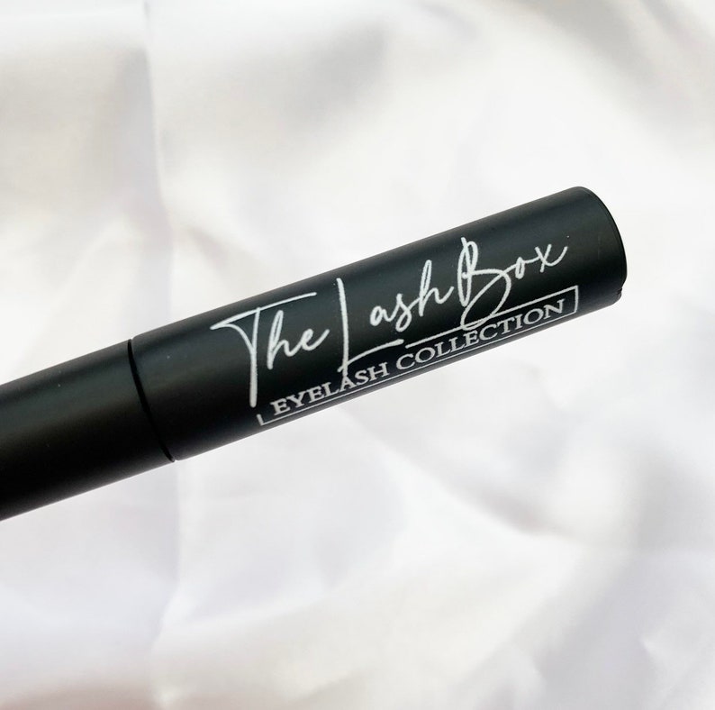 May include: A black tube with white text that reads "The Lash Box Eyelash Collection".