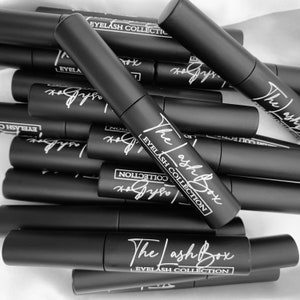 May include: A stack of black tubes with white text that reads "The Lash Box Eyelash Collection".