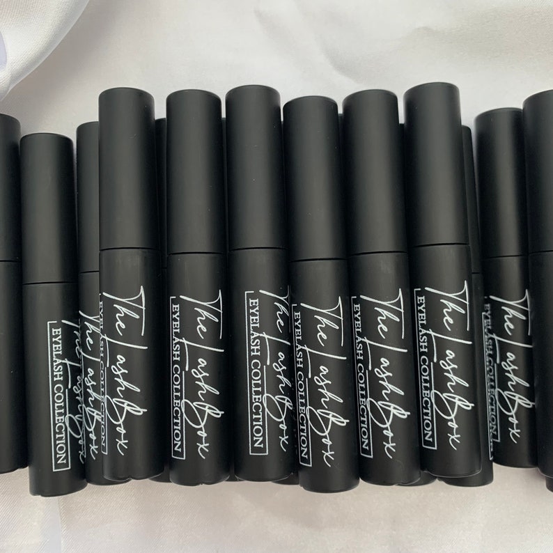May include: Multiple black bottles with white text that reads "The Lash Box Eyelash Collection" on each bottle.