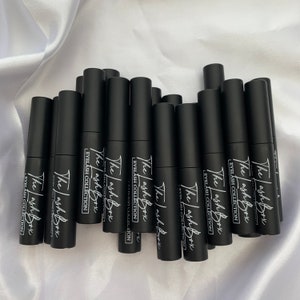 May include: A group of black tubes with white text that reads "The Lash Box Eyelash Collection".