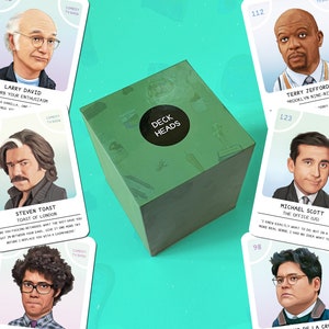 May include: A green box with the text "DECK HEADS" on a black circular sticker. The box is surrounded by cards featuring illustrations of various comedy TV show characters, including Larry David and Michael Scott.