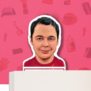 Puede incluir: Un marcapáginas rojo y blanco con una ilustración de dibujos animados de un hombre con cabello castaño y una camisa roja. El marcapáginas está diseñado para parecerse a una pegatina.