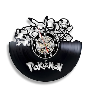 Può includere: Orologio in vinile nero con una silhouette di personaggi Pokémon, tra cui Pikachu, Squirtle e Bulbasaur. Il quadrante dell'orologio ha numeri e lancette argentati, e la parola "Pokémon" è stampata in bianco sotto il quadrante.