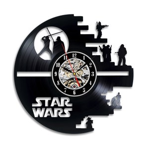 Könnte beinhalten: Eine schwarze Schallplattenuhr mit dem Star Wars-Logo und Figuren aus dem Film. Die Uhr ist in Form des Todessterns gestaltet und hat ein Zifferblatt mit römischen Ziffern.