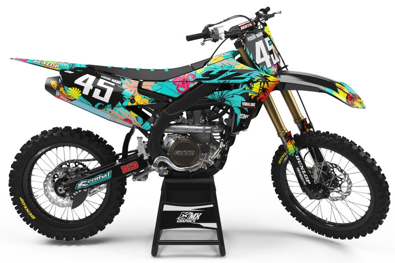 May include: A black and turquoise motocross bike with a floral design. The bike has a number plate with the number 45 on it. The bike is on a black stand.