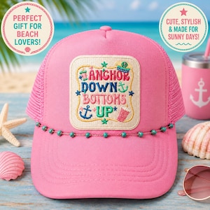 May include: A bright pink trucker hat with a mesh back and a beaded trim. The hat has an embroidered patch with the words "Anchor Down Bottoms Up" and nautical designs. A pink tumbler with an anchor is also in the image.