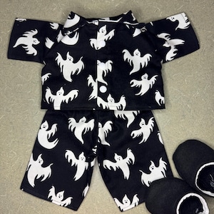 May include: Black pajama set with white ghost print, including a short-sleeved top and shorts. The set is accompanied by black slippers with white lining. A fun Halloween-themed sleepwear set.