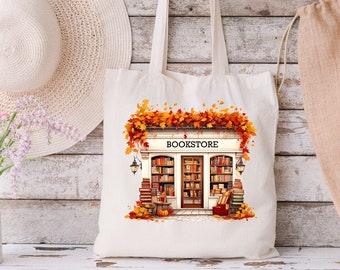 May include: A white tote bag with a bookstore illustration. The bookstore has a sign that says "BOOKSTORE" and is decorated with fall leaves.