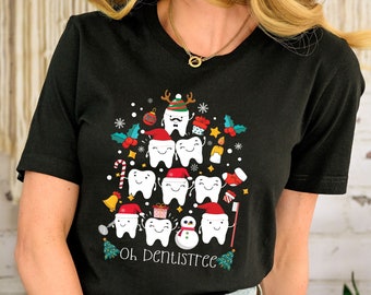 May include: A black t-shirt with a Christmas tree design made of teeth. The tree is decorated with ornaments, candy canes, and a snowman. The text "Oh Dentistree!" is printed below the tree.