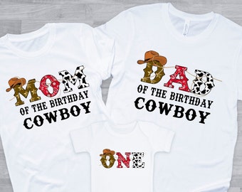 May include: White t-shirts with the text "Mom of the Birthday Cowboy", "Dad of the Birthday Cowboy", and a white onesie with the text "One" in a cowboy theme with brown, red, and black accents.