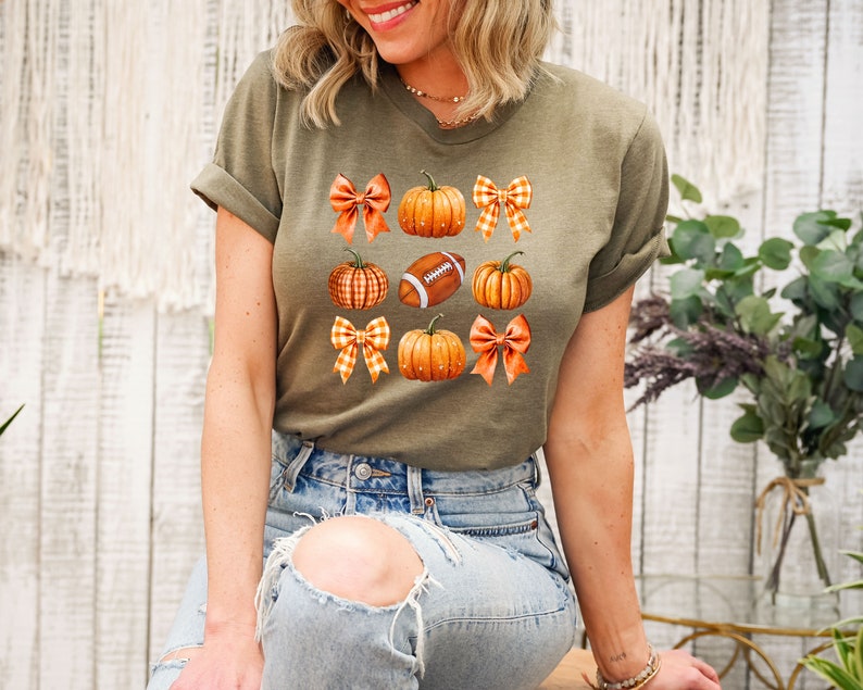 May include: A green t-shirt with a pattern of orange pumpkins, brown footballs, and orange and white gingham bows.