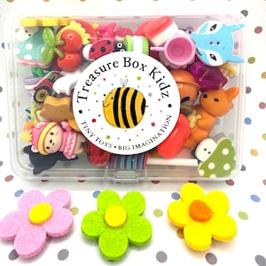 May include: A clear plastic box filled with colorful miniature toys, including a ladybug, a fox, a bee, a mushroom, and a cherry. The box has a white label with the text "Treasure Box Kidz. Tiny Toys. Big Imagination."