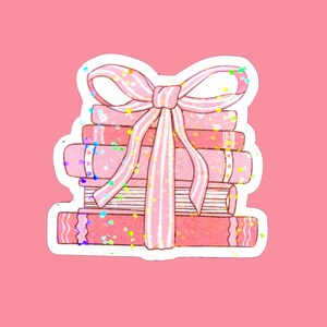 May include: A stack of pink books tied together with a pink ribbon bow. The books have a glittery texture.