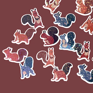 May include: A set of 14 colorful, glittery squirrel stickers. The squirrels are in various poses, some with their tails curled up, others with their tails straight out. The stickers are perfect for adding a touch of whimsy to any project.