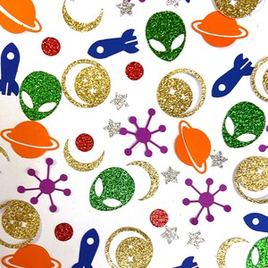 May include: A variety of colorful confetti featuring space-themed shapes, including aliens, rockets, planets, stars, and moons. The confetti is made of glitter paper and is perfect for adding a fun and festive touch to any party or celebration.