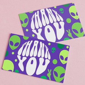 May include: Two purple cards with a white "Thank You" graphic in a retro font. The cards are decorated with green alien heads and green circles.