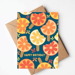 May include: A blue card with a pattern of orange and yellow citrus fruit slices on sticks. The text "HAPPY BIRTHDAY!" is printed in yellow on the card.