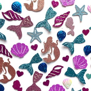 May include: Assortment of glitter mermaid and seashell shapes in various colors, including teal, pink, purple, and brown. The shapes include mermaids, seashells, starfish, and hearts.