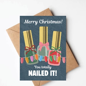 May include: A Christmas greeting card featuring three nail polish bottles with bows and a string of colorful lights. The card reads "Merry Christmas! You totally NAILED IT!" on a blue background, with a brown envelope.