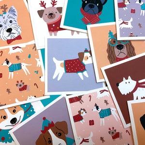 May include: A set of 10 Christmas cards featuring different illustrations of dogs wearing festive attire. The cards are printed on white cardstock and have a light blue background.