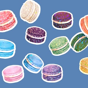 May include: A collection of colorful macarons with various fillings. The macarons are decorated with glitter and have a variety of colors, including pink, blue, green, purple, and orange.