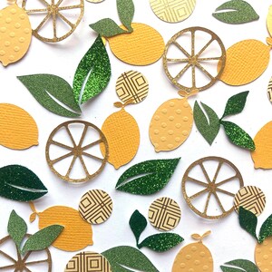 Pode incluir: Conjunto de recortes de papel amarelo e verde de lim&otilde;es, folhas e fatias de lim&atilde;o. As fatias de lim&atilde;o s&atilde;o de purpurina dourada e as folhas de purpurina verde.