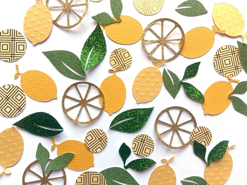 Pode incluir: Conjunto de recortes de papel amarelo e verde de lim&otilde;es, folhas e fatias de lim&atilde;o. As fatias de lim&atilde;o s&atilde;o de purpurina dourada e as folhas de purpurina verde.