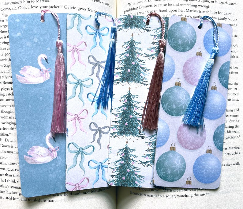 May include: Four different bookmark designs with tassels. The designs include swans, bows, Christmas trees, and ornaments. The bookmarks are all on a white background.