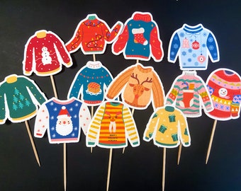 May include: Ten colorful Christmas sweater cupcake toppers with different designs, including a snowman, reindeer, Santa Claus, and a Christmas tree. The toppers are made of paper and have a stick attached to the back.