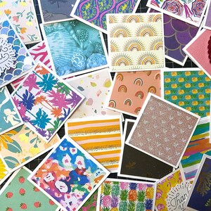 May include: A collection of colorful patterned paper squares, some with glitter, some with a textured surface, and some with a printed design. The patterns include pineapples, mermaids, rainbows, and palm trees. The squares are arranged in a random pattern on a black surface.