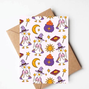 May include: A greeting card with a repeating pattern of cartoon geese dressed as witches, holding wands, and wearing purple hats and capes. The design includes moons, stars, suns, cauldrons, and spell books on a light pink background.