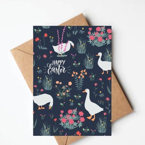 May include: A dark blue card with a white goose pattern and pink flowers. The text "Happy Easter" is written in white on the card.