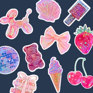 May include: A set of ten colorful stickers featuring various designs, including a seashell, a bow, a disco ball, a gummy bear, a strawberry, a cherry, an ice cream cone, a balloon animal, a stack of books, and a bottle of nail polish. All of the stickers have a glittery finish.