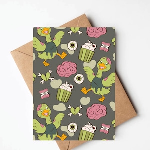 May include: Greeting card with a repeating pattern of zombie ducks, cupcakes, eyeballs, brains, and broken hearts on a gray background. The card is paired with a brown envelope, perfect for Halloween or spooky occasions.