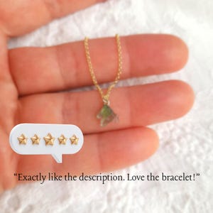 K&ouml;nnte beinhalten: Eine goldene Halskette mit einem Sternanh&auml;nger. Die Kette liegt auf einer Hand mit einer wei&szlig;en Sprechblase mit f&uuml;nf goldenen Sternen und dem Text "Genau wie in der Beschreibung. Ich liebe das Armband!"