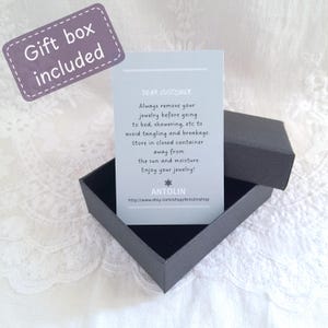 May include: A black jewellery box with a light blue card inside. The card has the text "Dear Customer" and instructions for caring for jewellery. The text on the card reads: "Always remove your jewellery before going to bed, showering, etc to avoid tangling and breakage. Store in closed container away from the sun and moisture. Enjoy your jewellery! Antolin http://www.etsy.com/shop/Antolinshop"