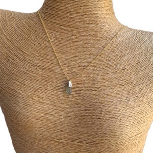 May include: A gold chain necklace with a green and silver crystal pendant.